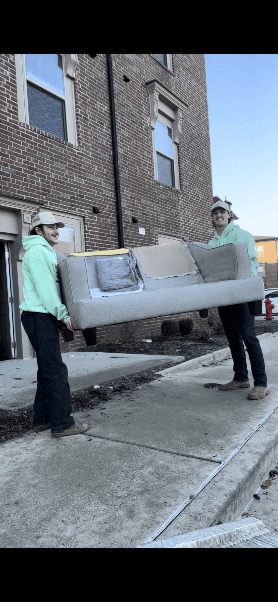 two junk removal employees removing a couch from a house in st louis, MO